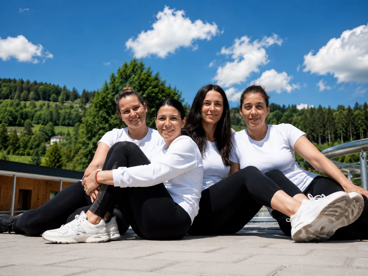 Das vierköpfige Team des Restaurants sitzt zusammen auf der Terrasse am Freibad Neumarkt, im Hintergrund Wald und blauer Himmel